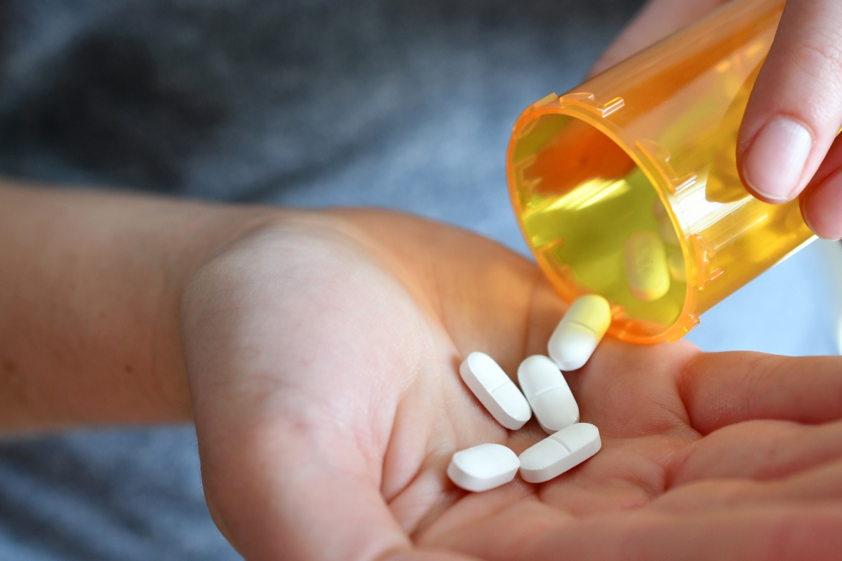person pouring pills into their hand while disregarding opioid overdose symptoms